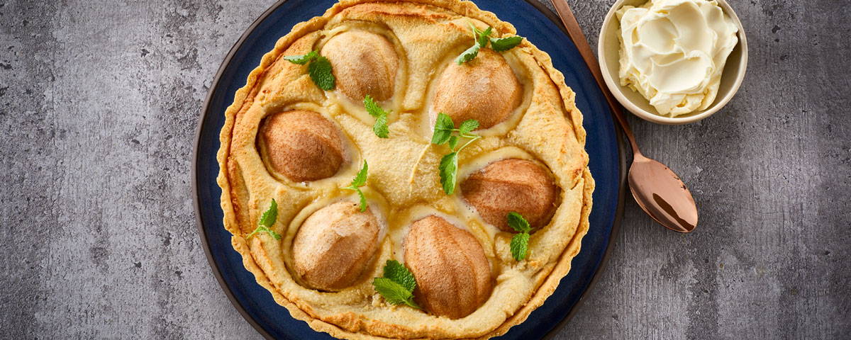 Billede af en pæretærte, samt en skål med Double Fraiche.