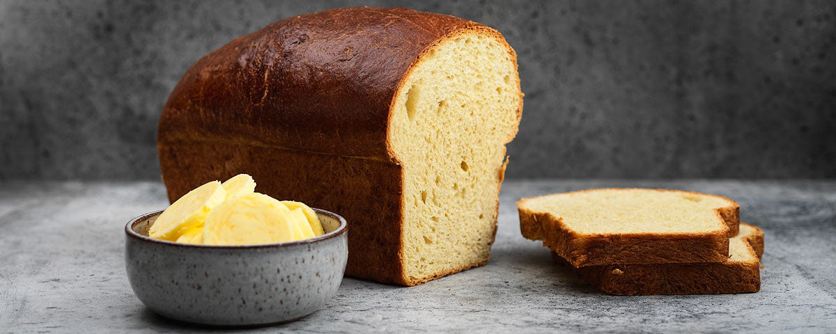 Billede af briochebrød, med skårede skiver, samt et skål med smør. 