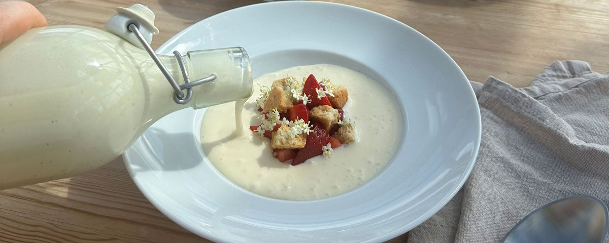 Billede af en skål med koldskål, jordbær, kammerjunker og hyldeblomster. 