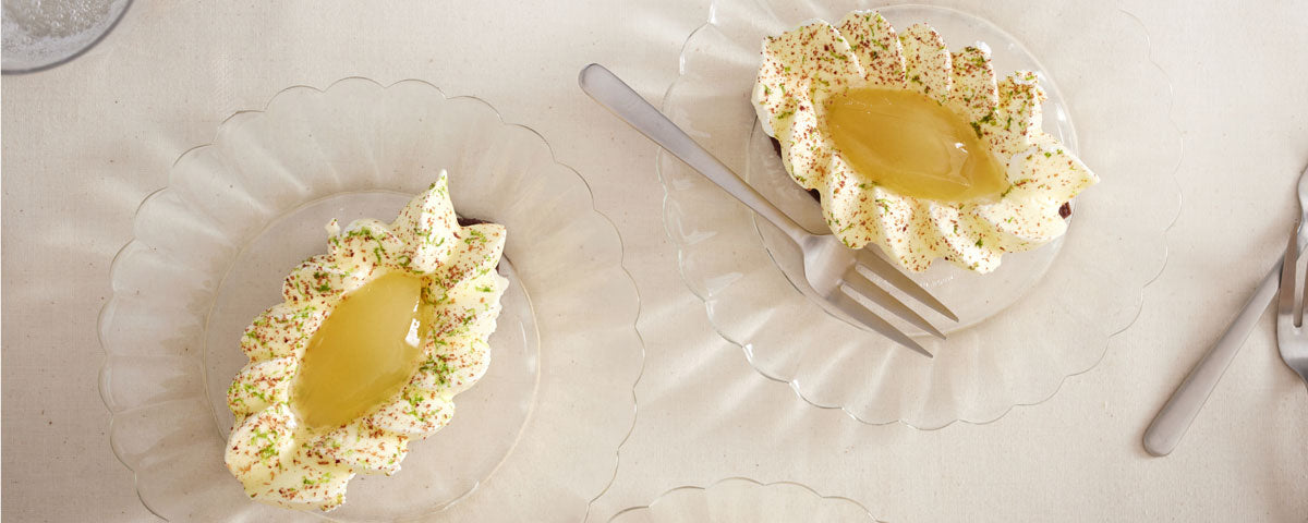 Billede af to små flødeskumskager, med pocheret pære serveret ovenpå. 