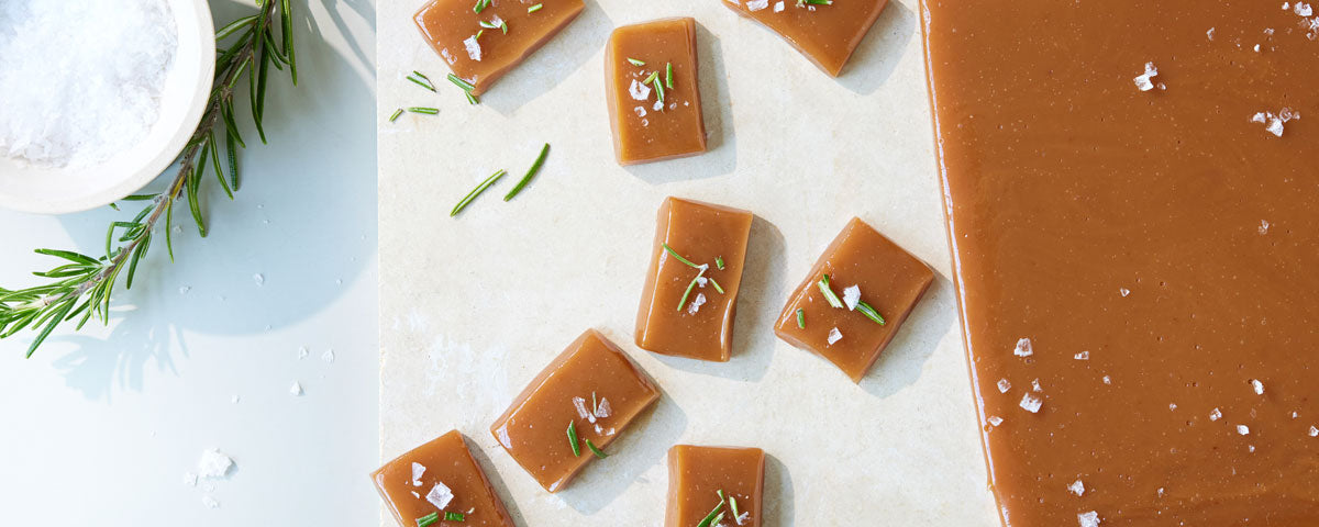 Billede af et stykke bagepapir med udskårne flødekarameller. 