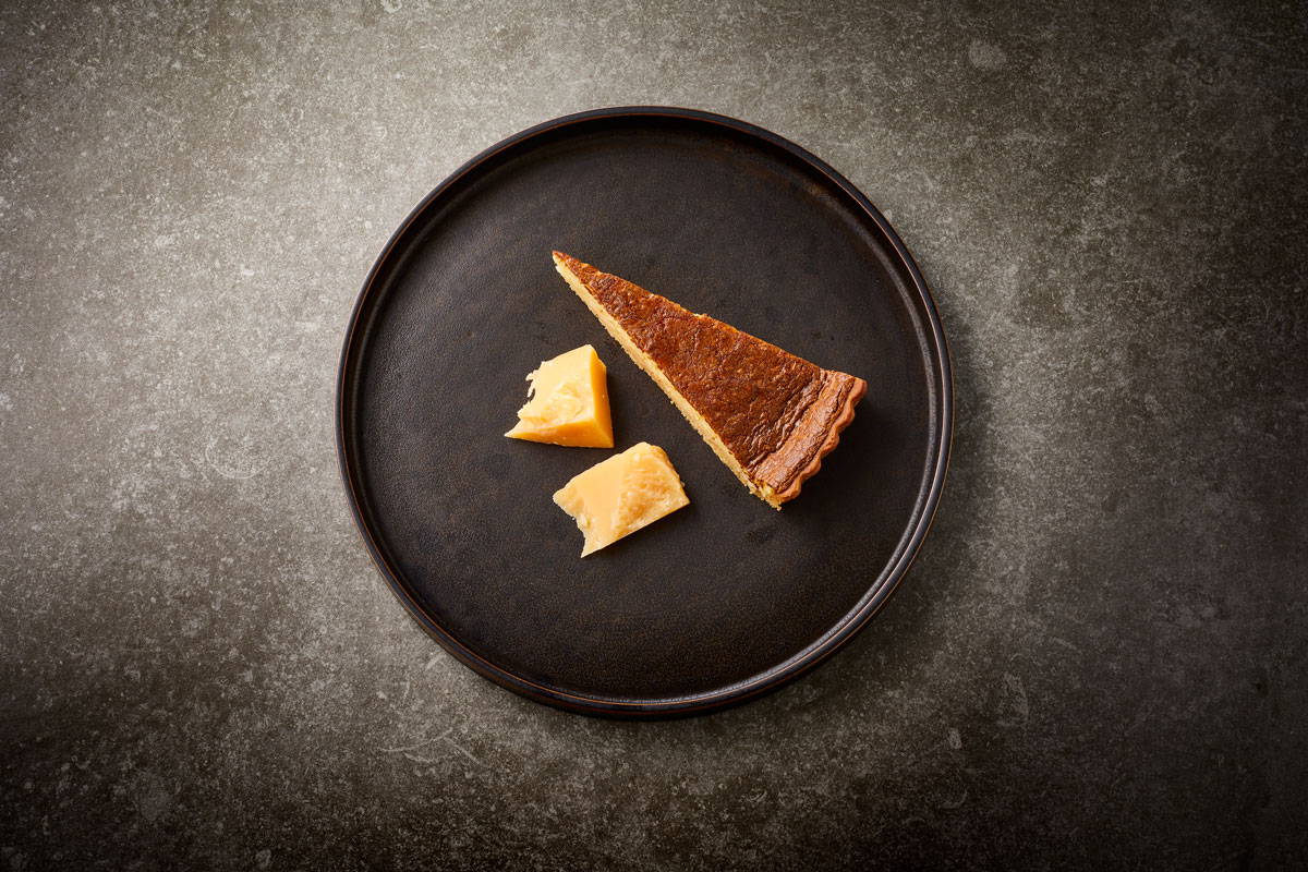 Billede af en stykke Havgus-tærte, serveret med stykker af ost. 