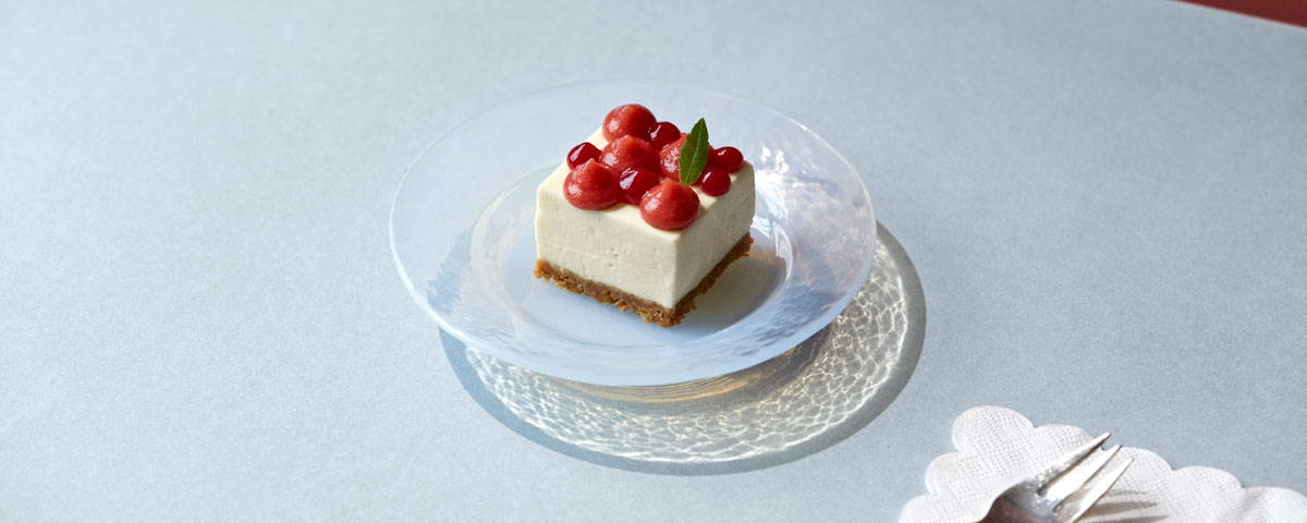 Billede af cheesecake, toppet med jordbærpuré og hele bær. 