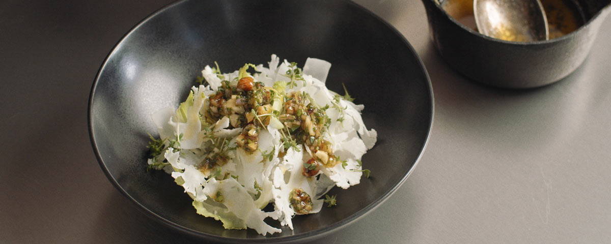 Billede af skål med salat serveret med Brunet smør vinaigrette ovenpå. 